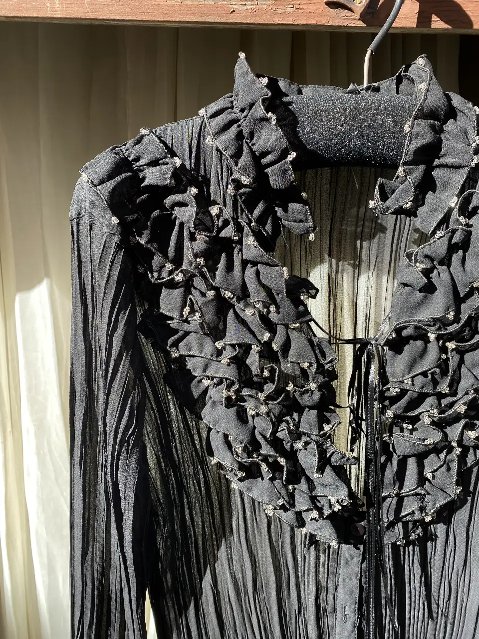 Blusa negra con detalles de volados y apliques brillantes. Ideal para un look elegante y sofisticado.