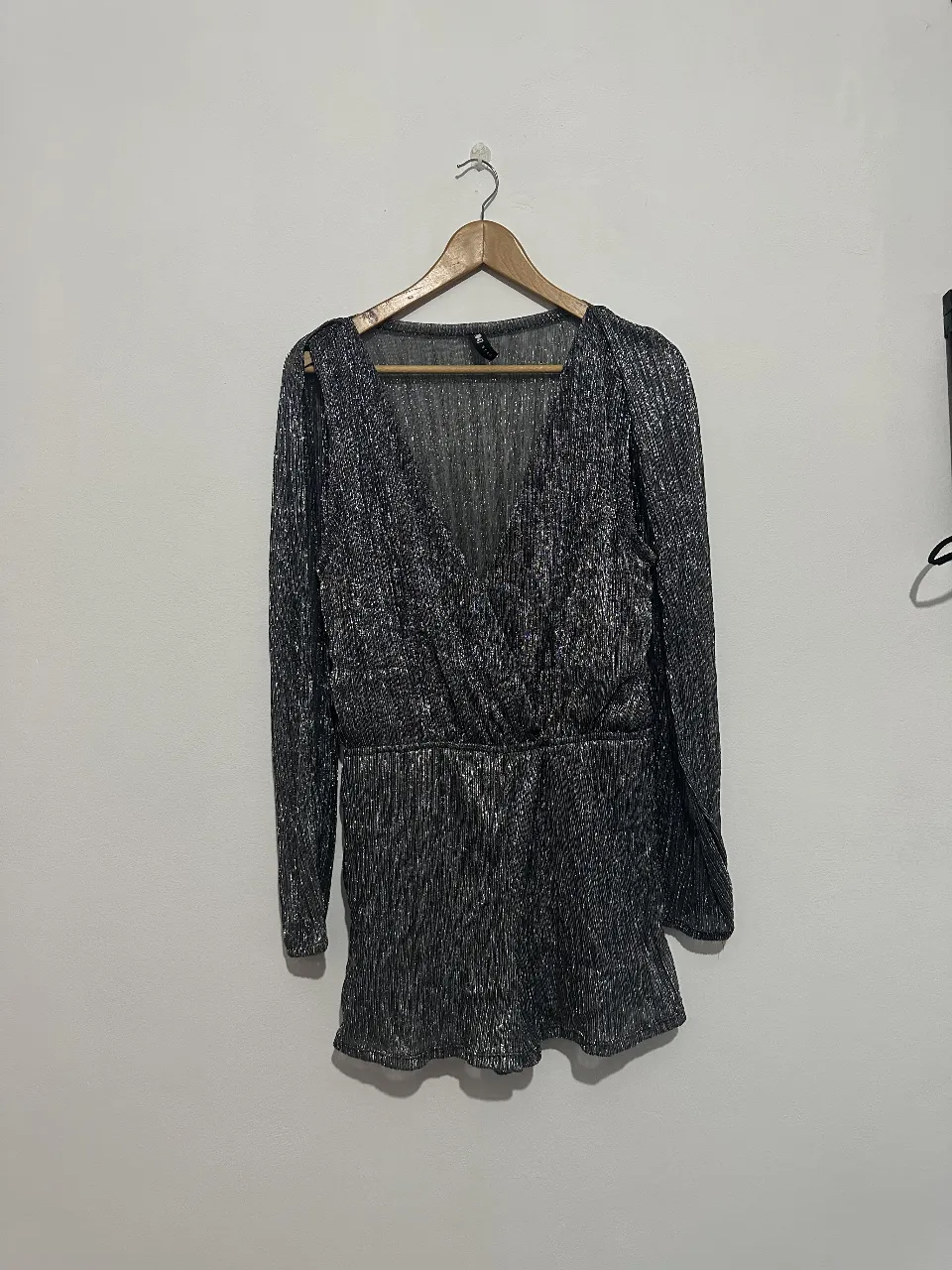 Mono / vestido corto de fiesta con brillo, escote en V y mangas largas abiertas. Con short negro incluido. Ideal para eventos especiales.