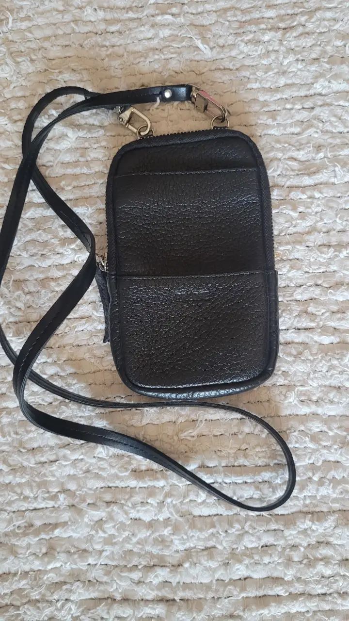 Cartera bandolera negra de cuero, ideal para llevar lo esencial. Cuenta con cierre y correa