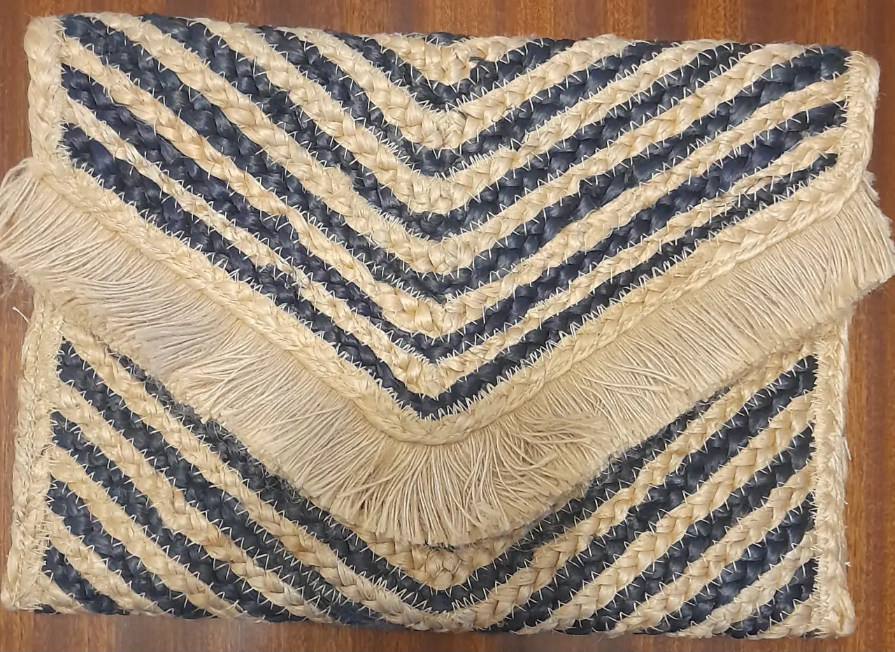 Cartera de mano artesanal con diseño chevron en tonos crudo y azul marino. Detalles de flecos en la solapa. Ideal para un look bohemio y casual.