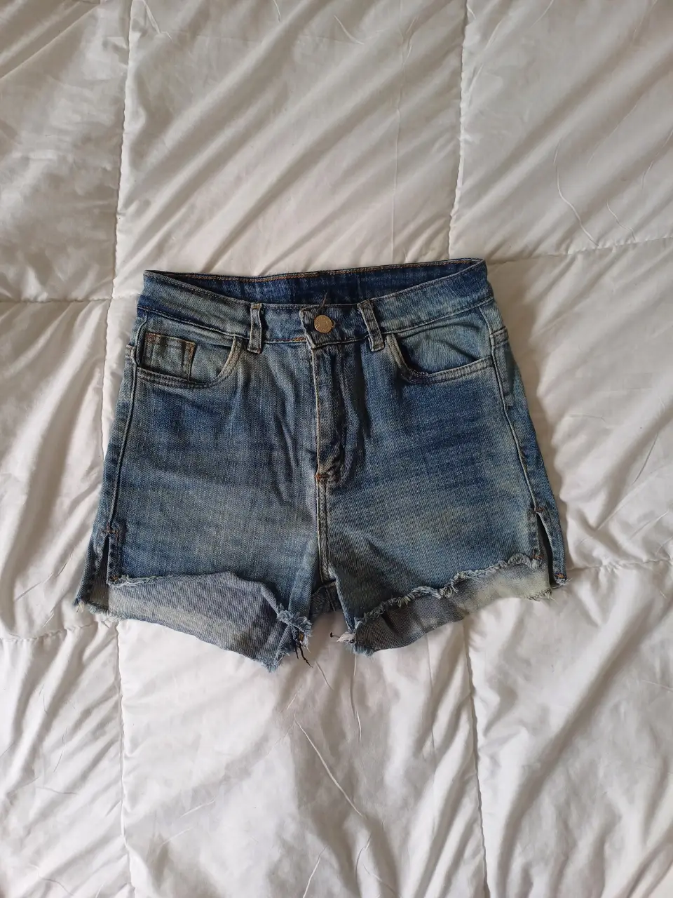 Short de jean de mujer, tiro medio, con detalles de desgaste y corte desflecado en los bordes. Es muy corto y al cuerpo.