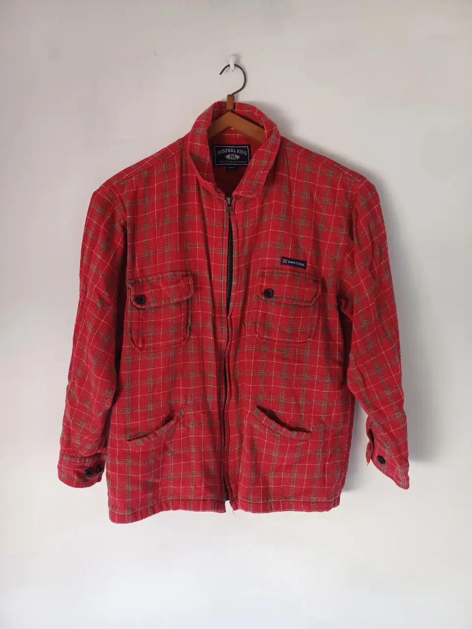 Campera a cuadros roja, con cierre y bolsillos. Es para niños pero a una persona petite le queda bien, pero corteli en las mangas.