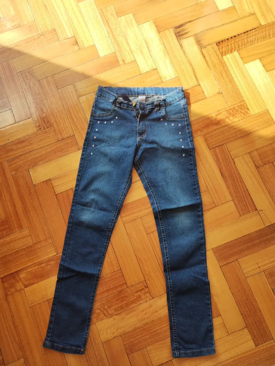 Jean azul de niña, corte recto, con detalles de estrellas bordadas en la parte delantera. Ideal para un look casual y cómodo.