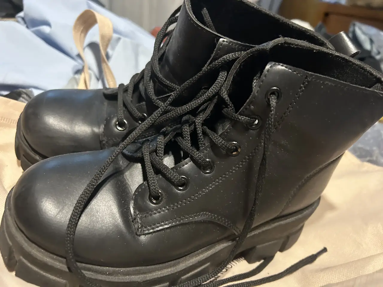 Borcegos negros de cuero sintético con suela gruesa. Cordones y detalles clásicos. Ideales para un look urbano y moderno.