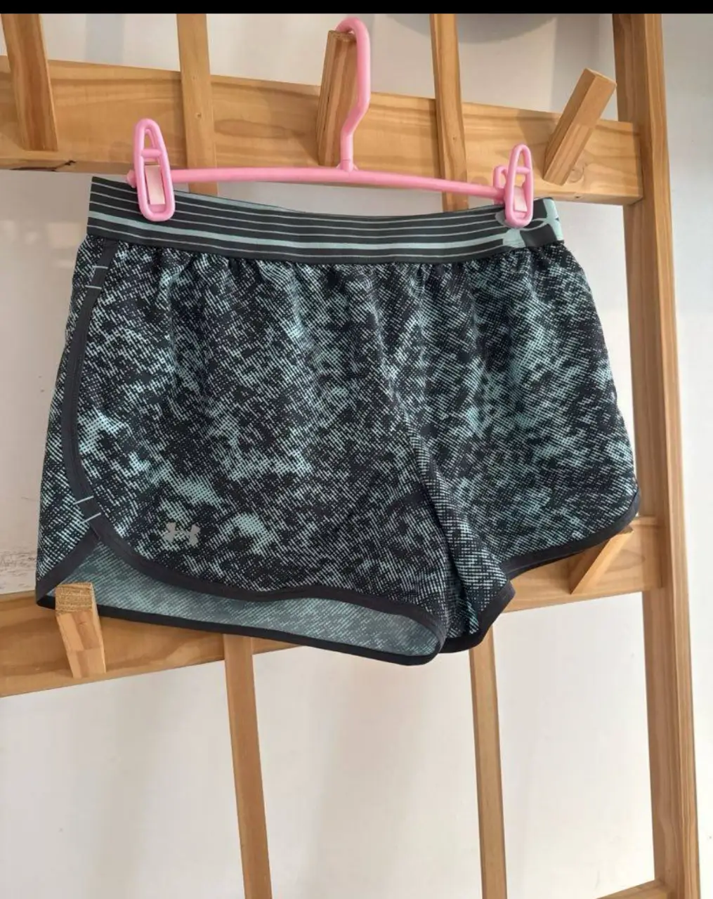 Short deportivo Under Armour para mujer, con estampado en tonos grises y celestes. Ideal para running y entrenamientos.