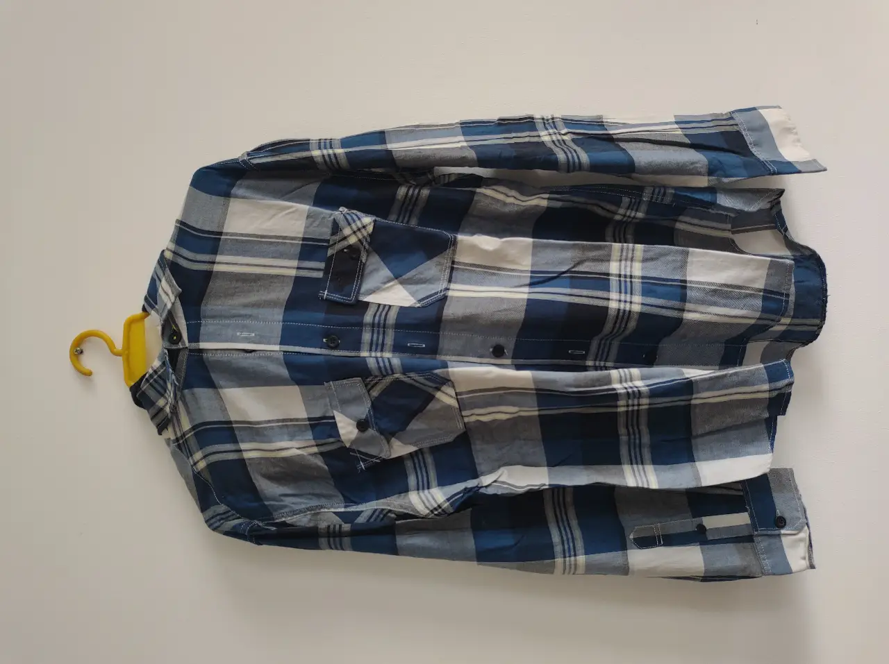 Camisa a cuadros azul y blanca de hombre, con dos bolsillos delanteros y capucha. Ideal para un look casual y relajado.
