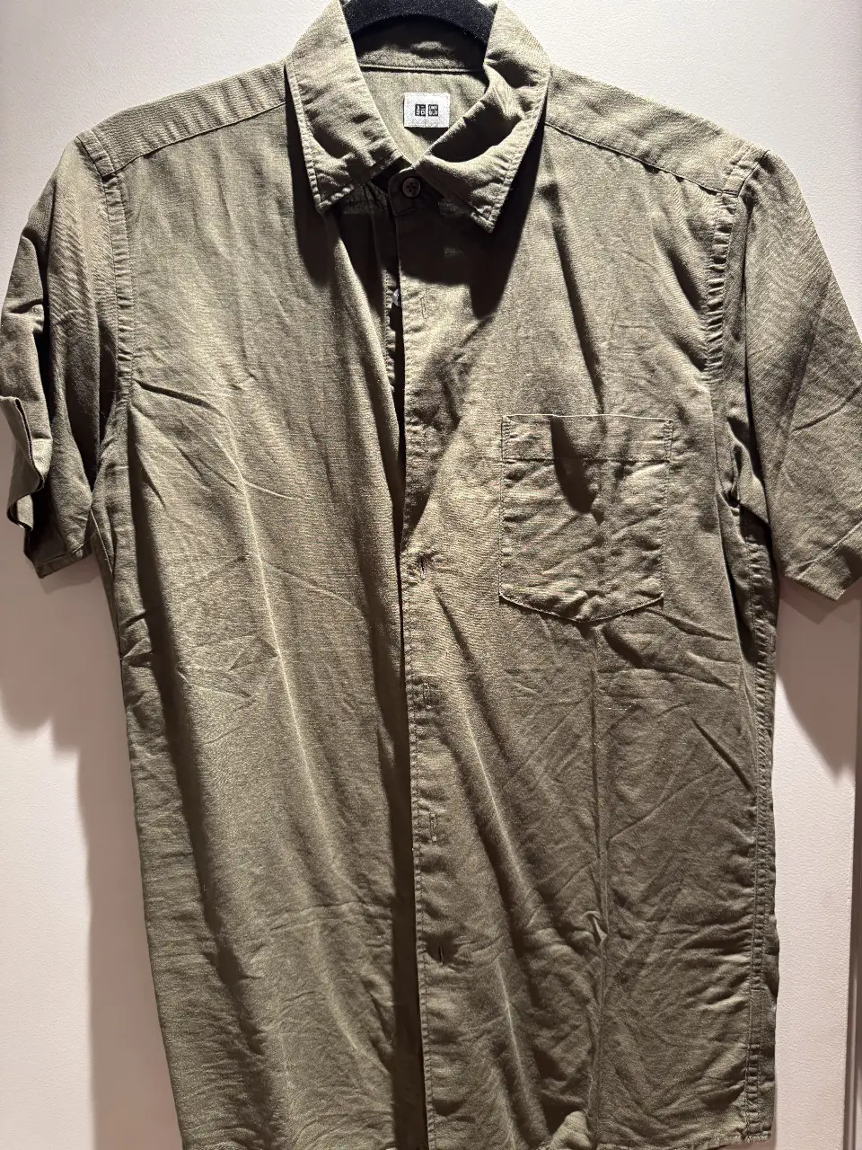 Camisa de hombre de manga corta, color verde oscuro, de la marca Uniqlo. Ideal para un look casual y cómodo.
