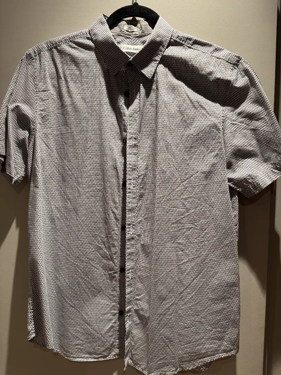Camisa de hombre Calvin Klein con estampado geométrico en tonos grises y blancos. Confeccionada en algodón, manga corta y talle M.