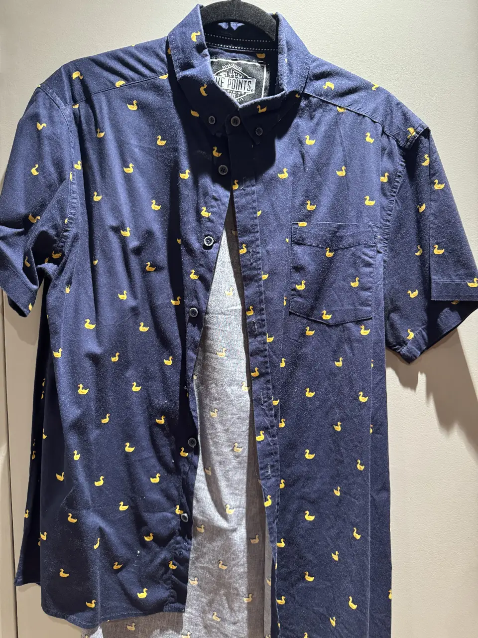 Camisa de hombre azul marino con estampado de patitos amarillos. De manga corta, con bolsillo en el pecho y botones. Marca Five Points, talle M.