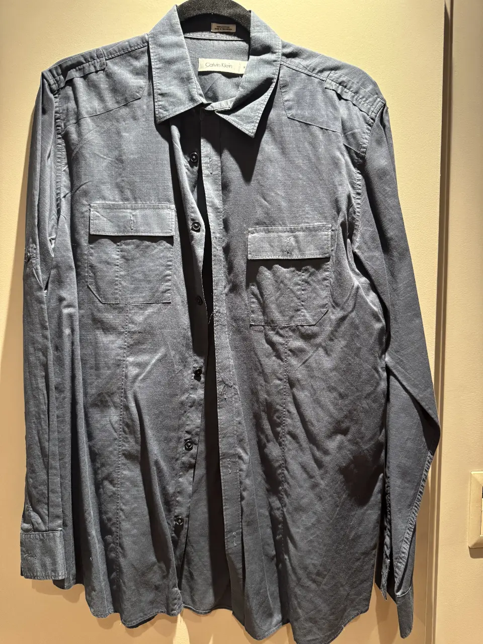 Camisa de hombre Calvin Klein, manga larga, color azul, con dos bolsillos delanteros. Talle M. Ideal para un look casual o de trabajo.