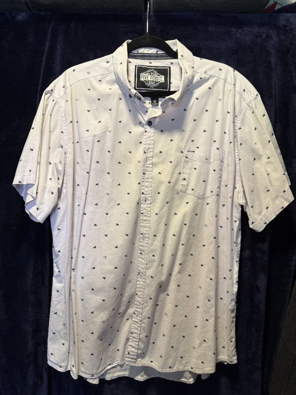 Camisa de hombre estampada con pequeños dibujos en color negro. Corte clásico, manga corta y cuello con botones. Ideal para un look casual y fresco.