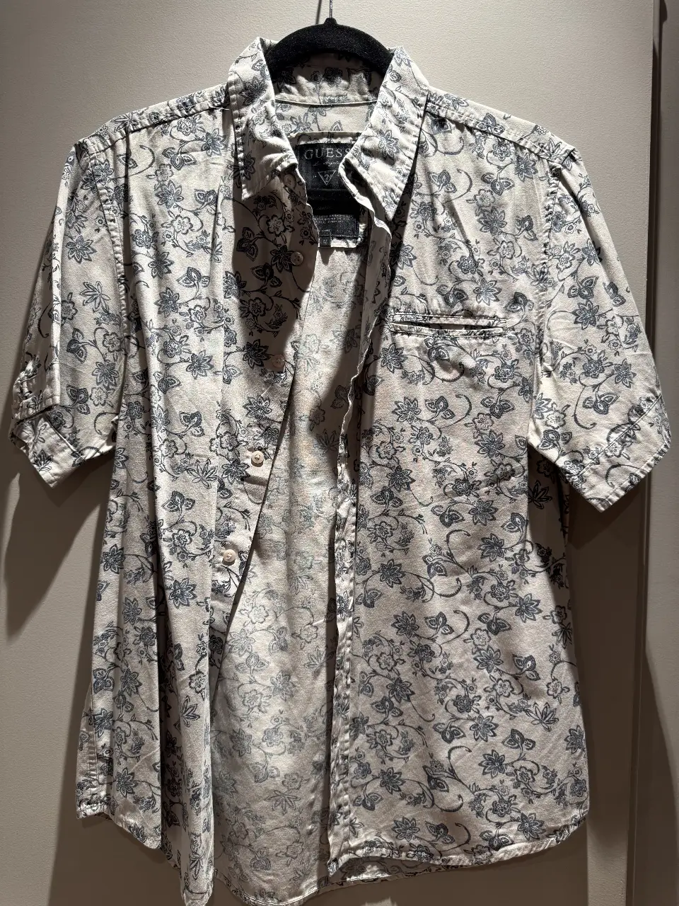 Camisa Guess de hombre, manga corta, con estampado floral en tonos blanco y azul. Ideal para un look casual y fresco.