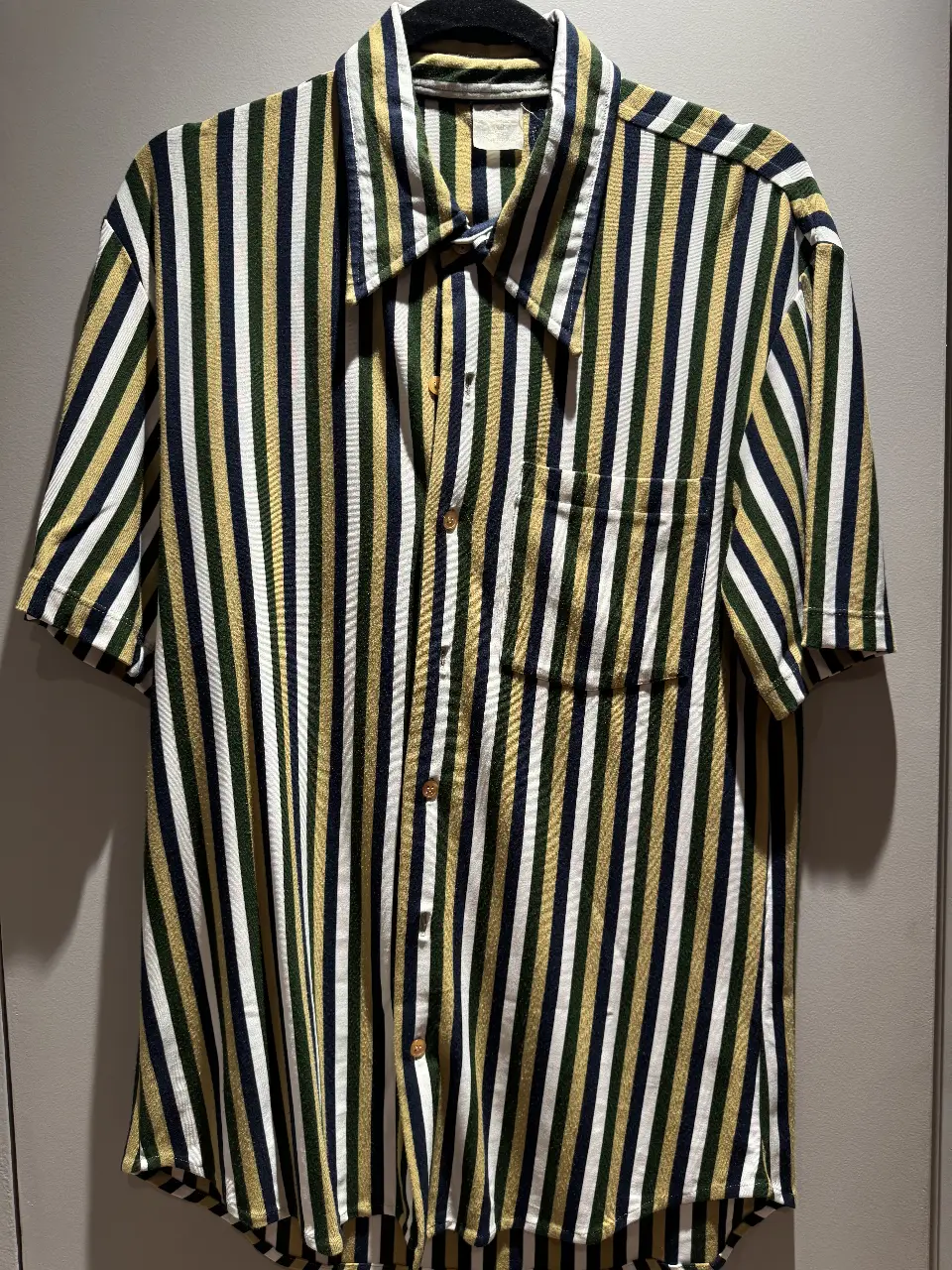 Camisa a rayas verticales en tonos verde, blanco y amarillo. Corte clásico con bolsillo en el pecho y mangas cortas. Ideal para un look casual y fresco.