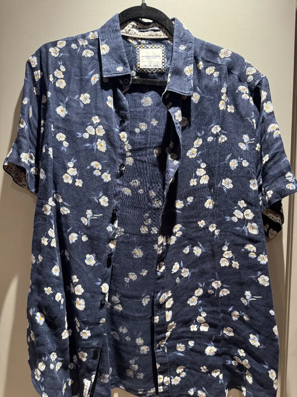 Camisa de hombre con estampado floral en tonos azul marino y blanco. Diseño con cuello clásico y manga corta. Ideal para un look casual y fresco.