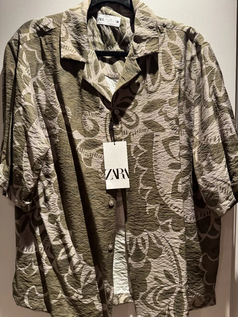 Camisa estampada de hombre de la marca Zara, con un diseño floral en tonos verdes y crudos. Ideal para un look casual y fresco.