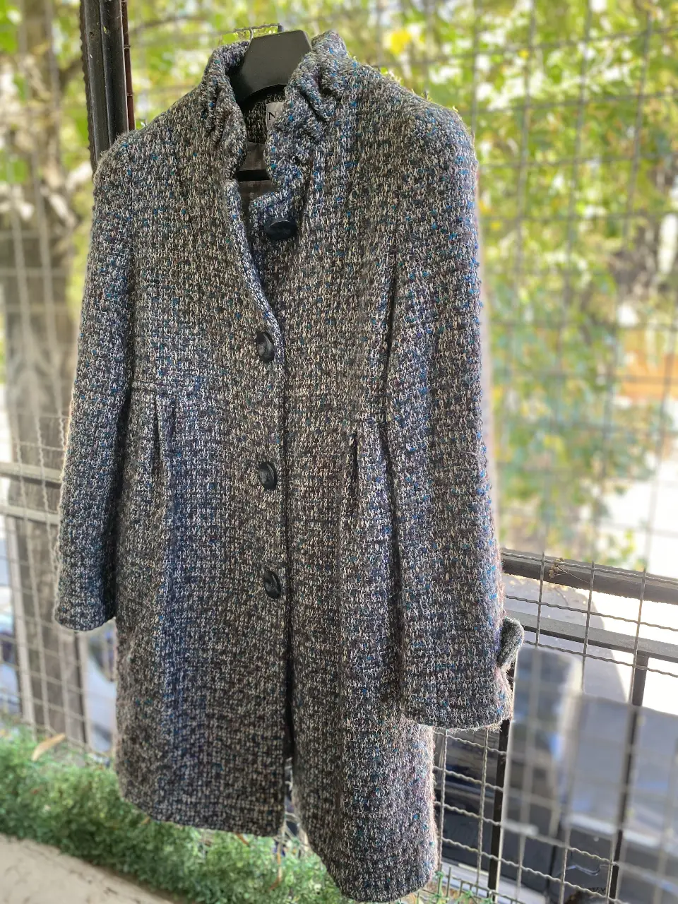 Tapado de mujer, largo a la rodilla, con diseño tweed en tonos grises y azules. Posee cuello alto y botones. Ideal para el invierno.