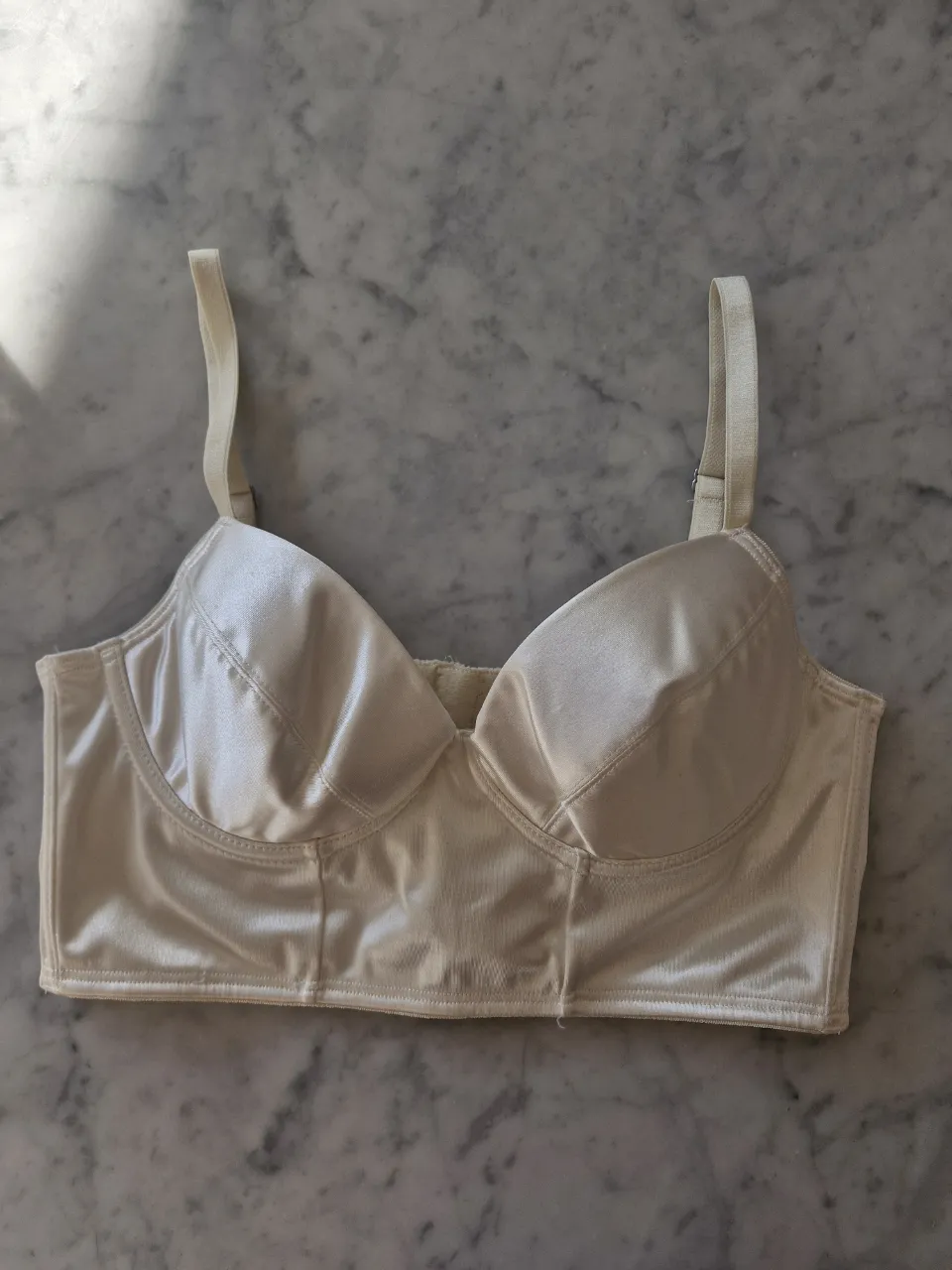 Corpiño largo de satén color crudo, con detalles de costuras que realzan la silueta. Ideal para usar como top o debajo de prendas transparentes. Posee breteles regulables y cierre de ganchitos en la espalda. Para 90 de busto aprox