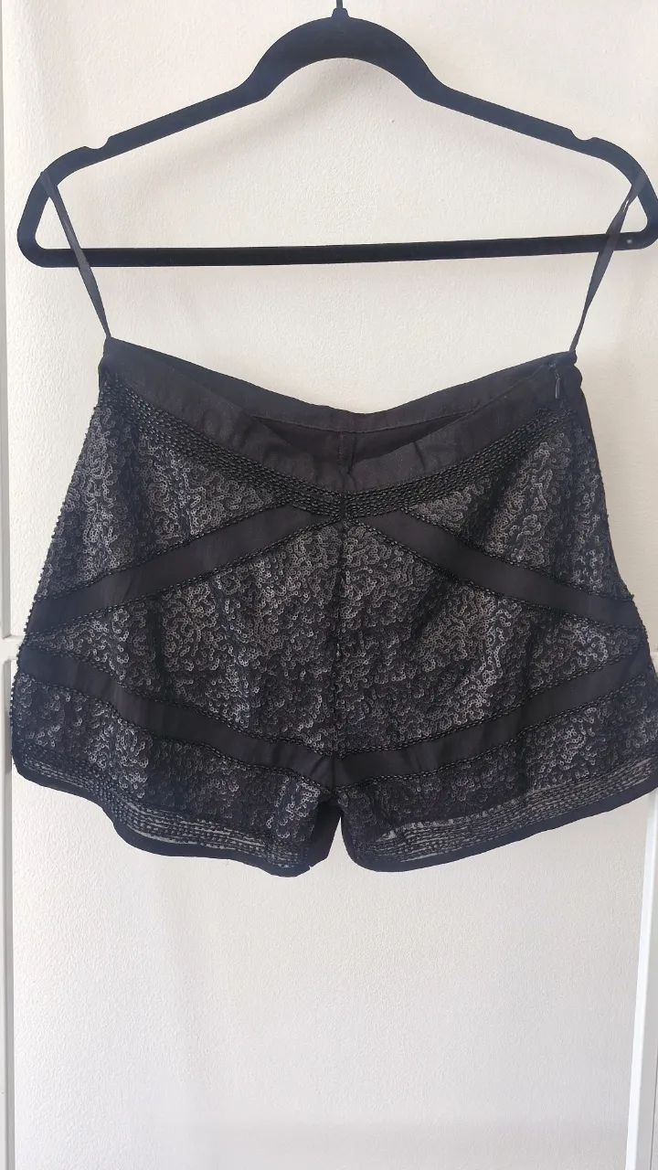 Shorts negros con lentejuelas en el frente. detalles que se ven en la foto. medidas en la foto tomadas en plano: cintura 35cm, cadera 47cm, tiro 32cm, largo 36cm. Sería para un 26 de pantalon. tiro medio-alto