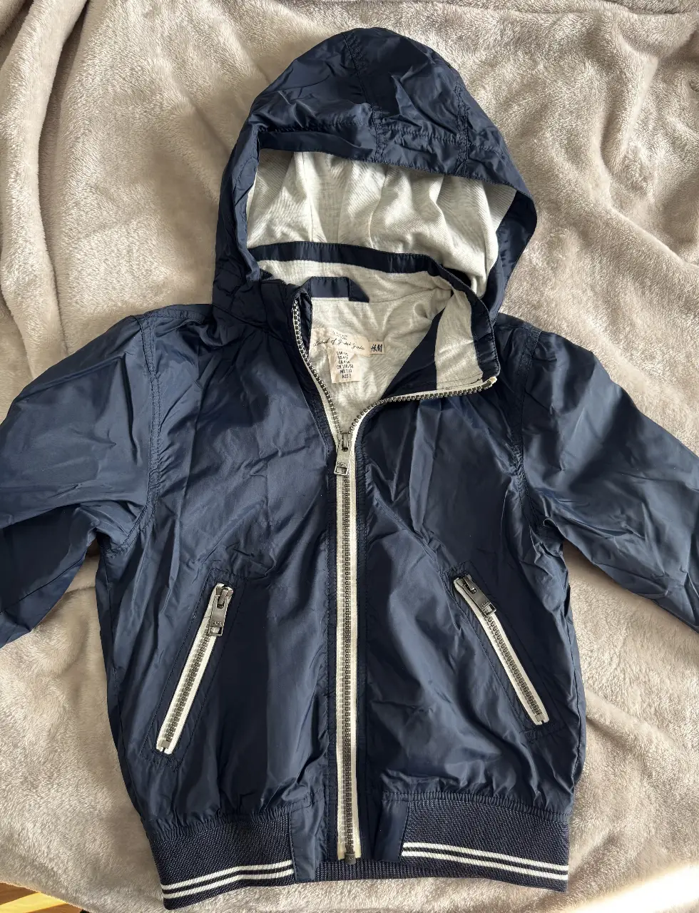 Campera deportiva azul marino para niño con capucha y cierre. Marca H&M, talle 4-5 años. Ideal para abrigo ligero y actividades al aire libre.
