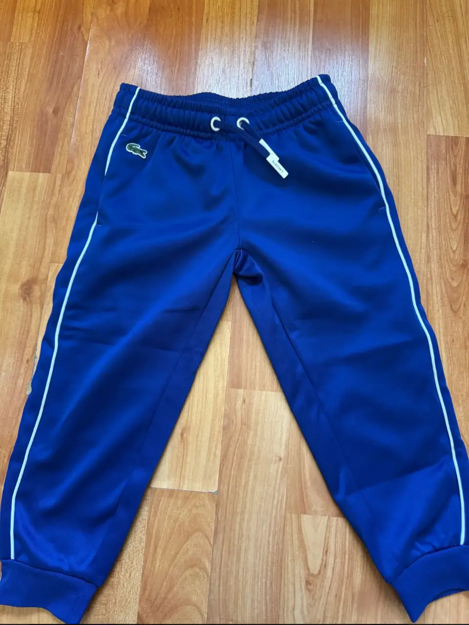 Pantalón deportivo azul de niño, con detalles blancos y logo de Lacoste. Talle 4.