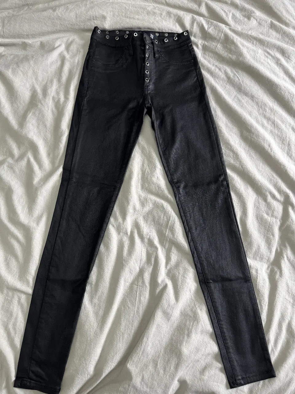 Pantalón de jean negro Kosiuko con detalles de ojales en la cintura y botones. Corte skinny, ideal para un look moderno y versátil.