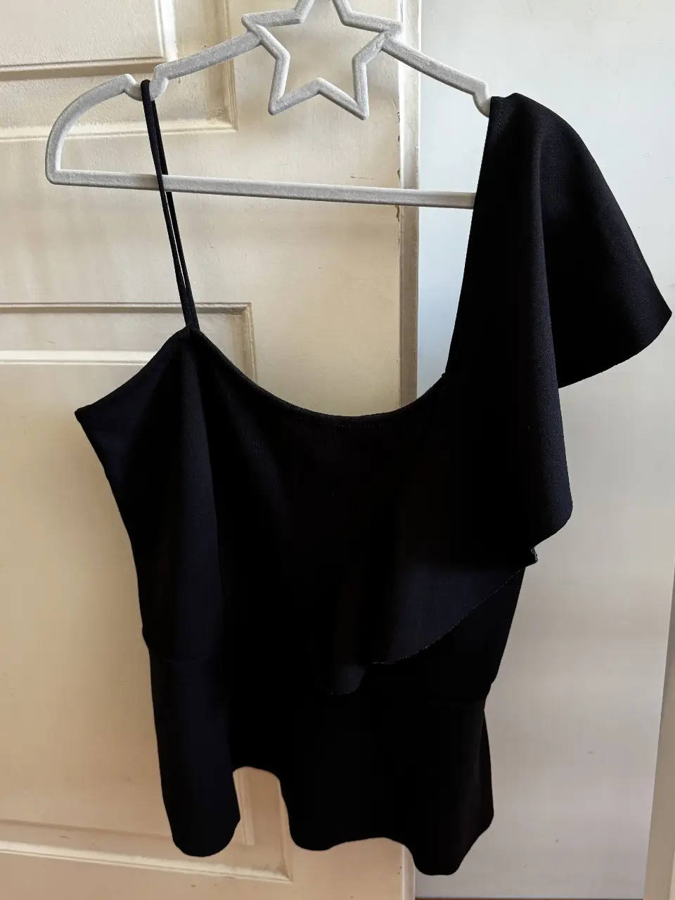 Top negro de diseño asimétrico con un solo hombro y detalle de volado. Ideal para una salida o evento especial. Marca Tucci, talle XS.