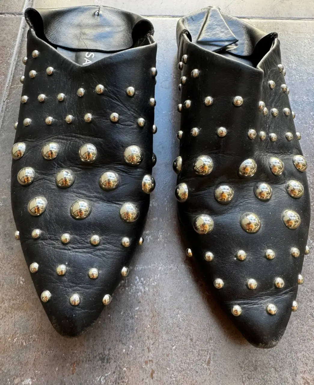 Zuecos Sarkany negros de cuero con tachas plateadas. Ideales para un look moderno y canchero.