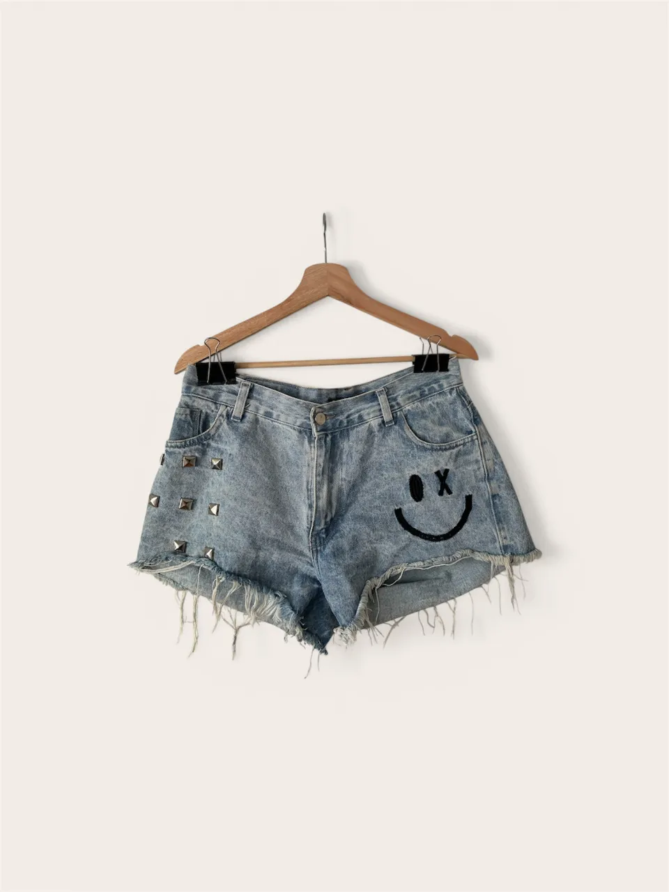Shorts de jean tiro alto con tachas y bordado de carita feliz. Un diseño único y canchero para destacar tu estilo.