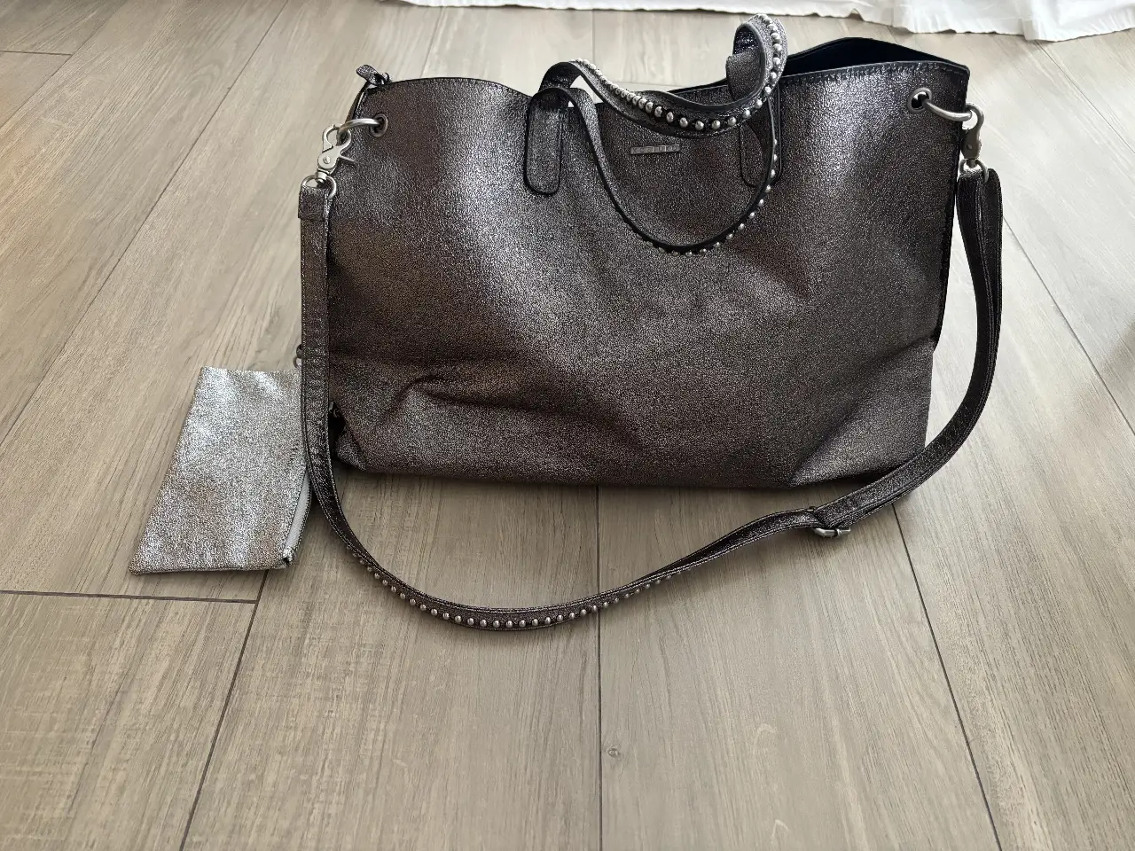 Cartera tipo tote bag de la marca Kosiuko, color gris metalizado. Incluye un sobre a juego. Ideal para llevar todo lo necesario con estilo.