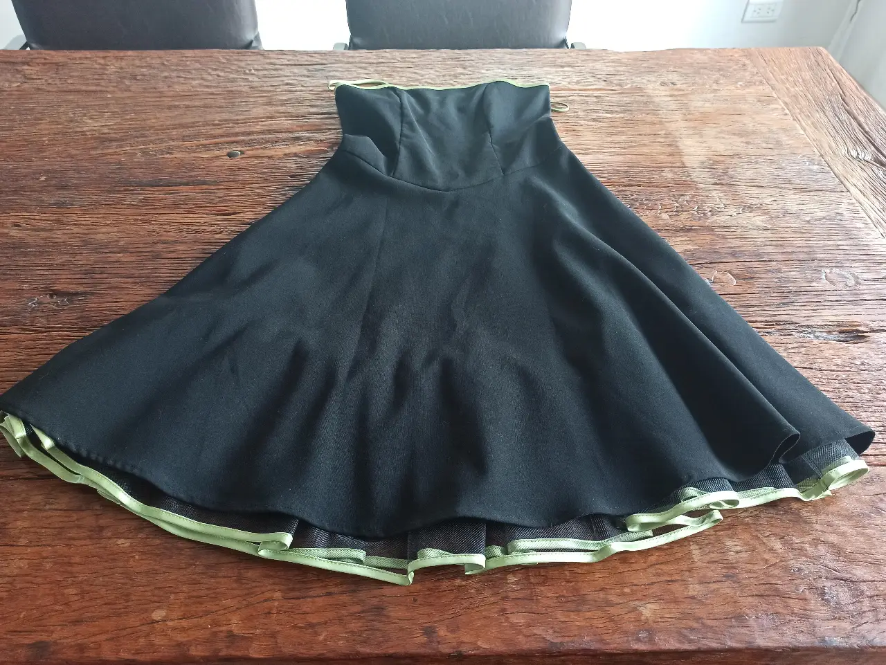 Vestido strapless negro con detalles en verde. Ideal para fiestas y eventos especiales. Diseño elegante y moderno.