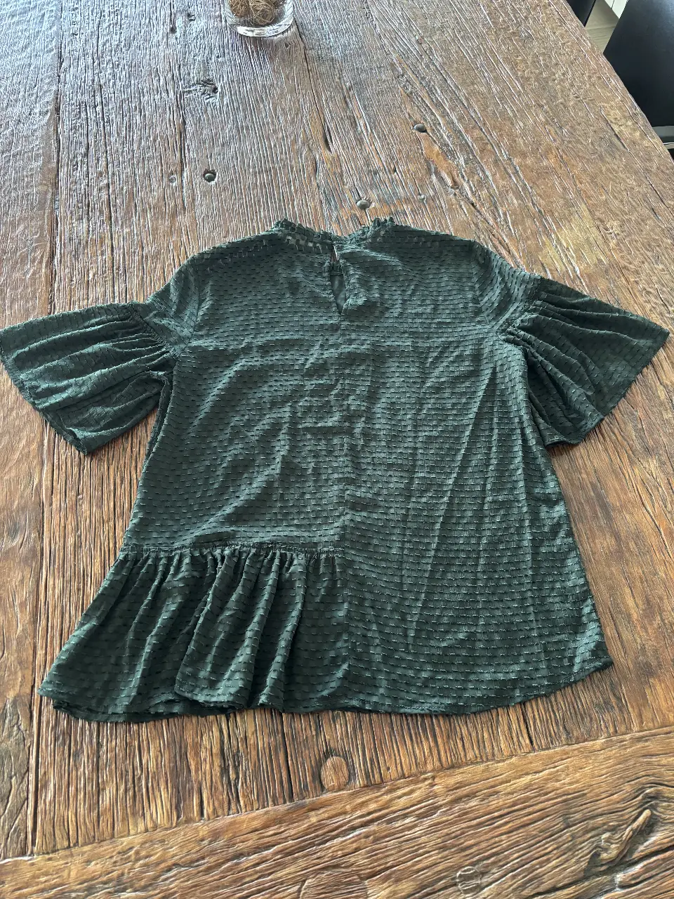 Blusa verde oscuro con mangas amplias y detalle de volado en el bajo. Ideal para un look elegante y moderno.