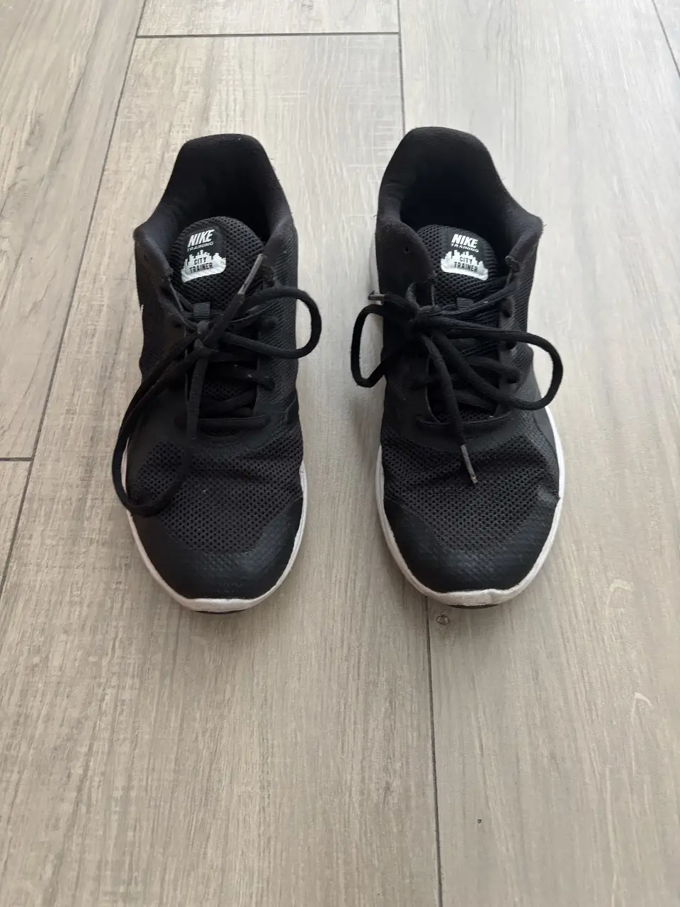 Zapatillas Nike negras con detalles blancos. Ideales para entrenamientos y uso diario. Tienen un diseño moderno y cómodo.