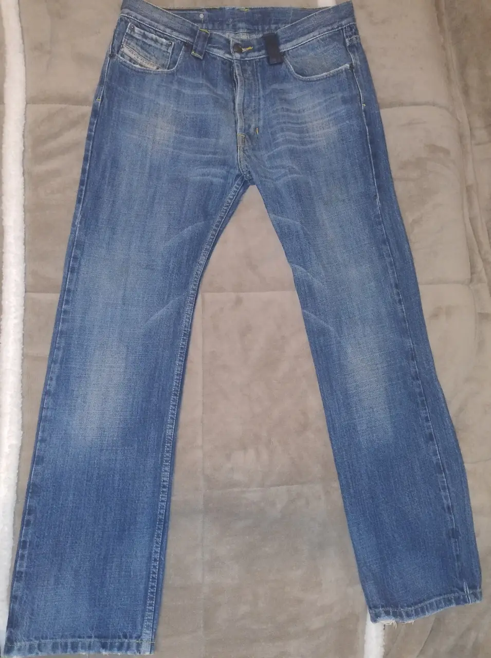 Jeans rectos de hombre, color azul gastado, con cierre de botones y bolsillos delanteros y traseros. Talle 32.