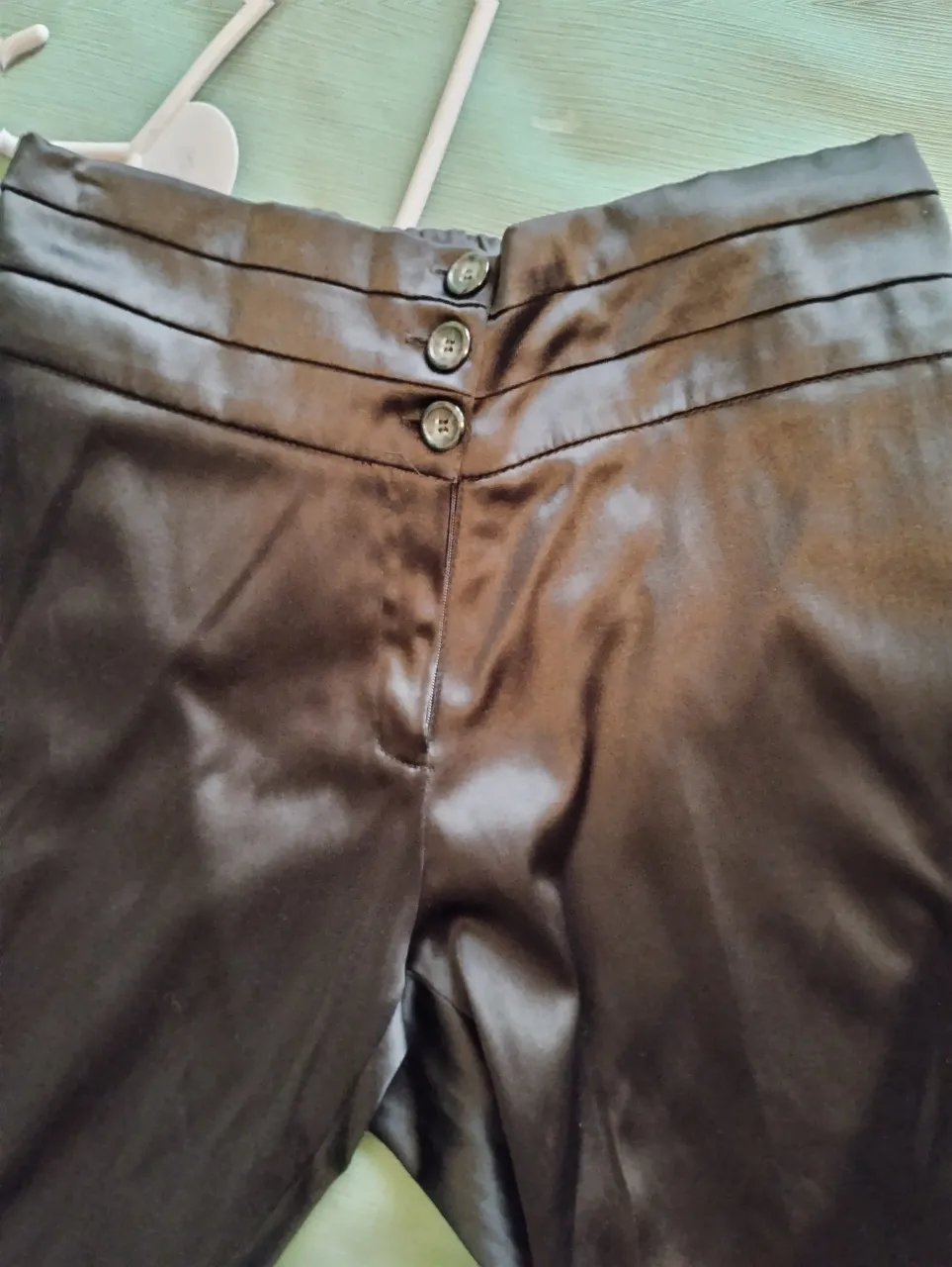 Pantalón sastrero negro de satén con detalles de botones y cintura alta. Tres botones por delante y elastizado de atras. Recto, buen calce. Ideal para un look elegante y sofisticado.