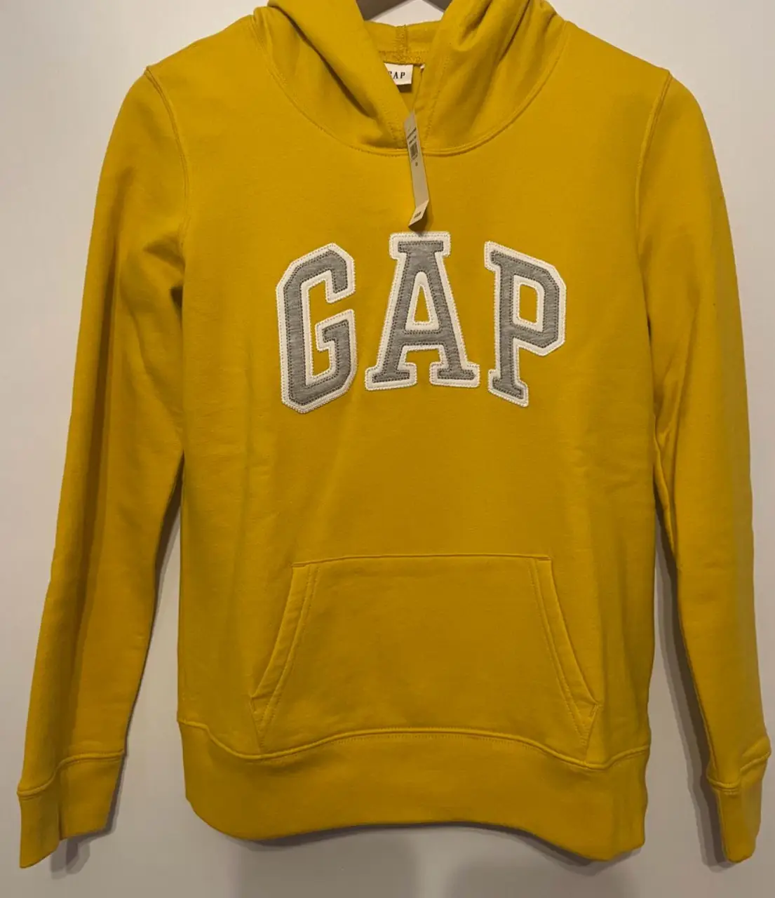 Buzo canguro GAP amarillo con logo "GAP" en gris. Ideal para un look casual y cómodo. Color mostaza/ocre