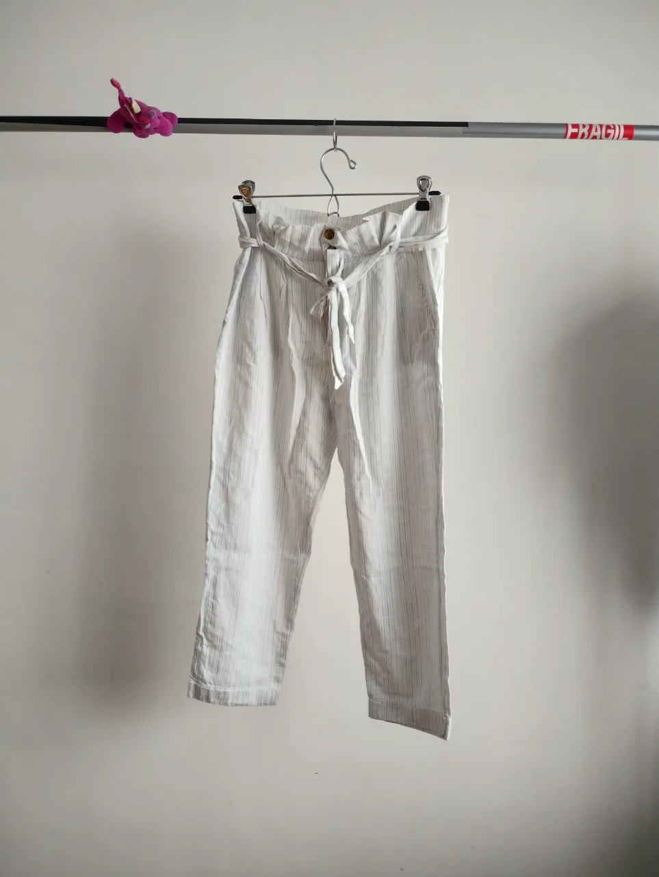 Pantalón de lino blanco con finas rayas verticales celestes. Posee lazo para atar en la cintura y dos botones. Corte recto y tiro alto, ideal para un look fresco y casual. nuevo. tobillero. talle S va para 36. tiro alto.
