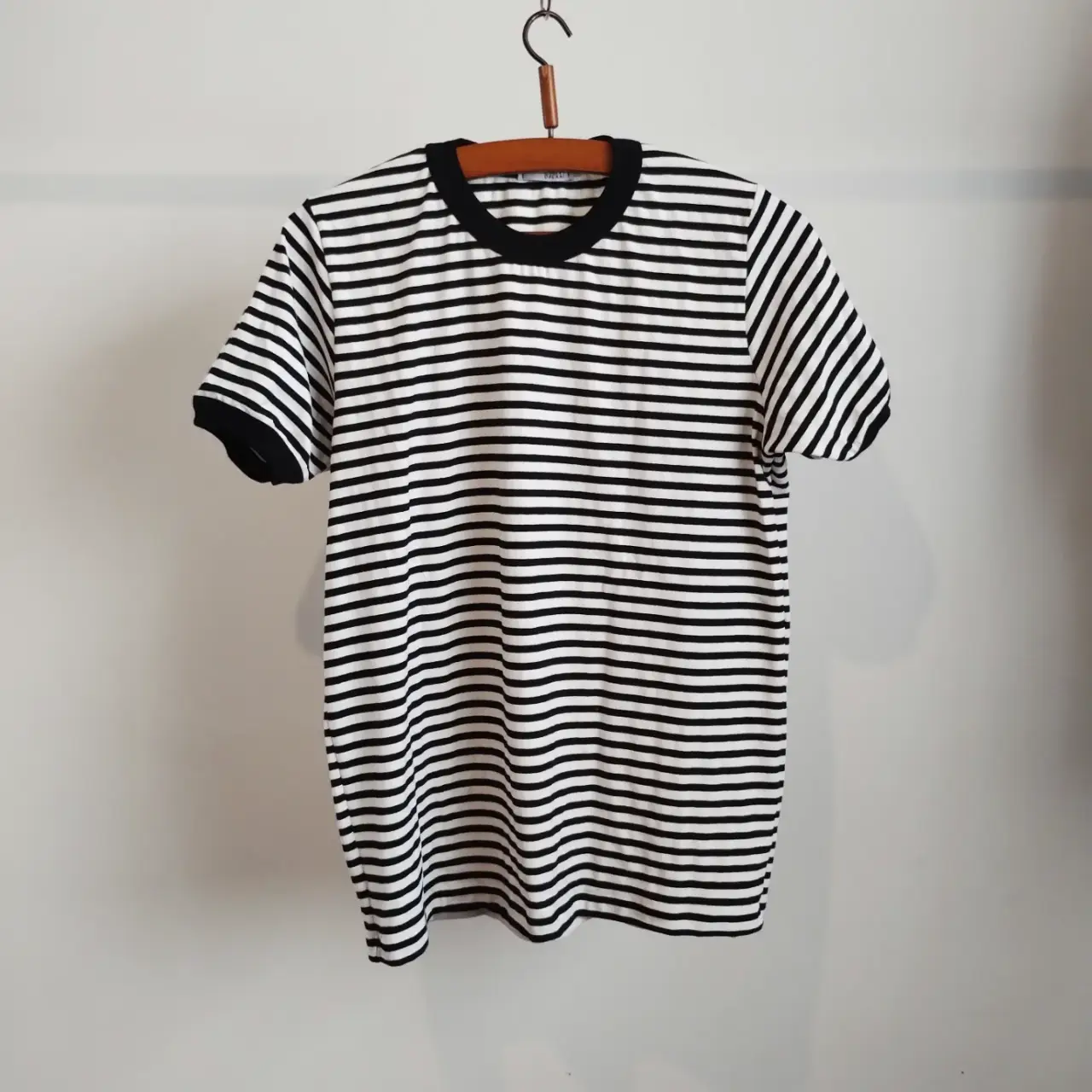 Remera a rayas horizontales en blanco y negro, con cuello y mangas en negro. Corte clásico y cómodo, ideal para un look casual y versátil.