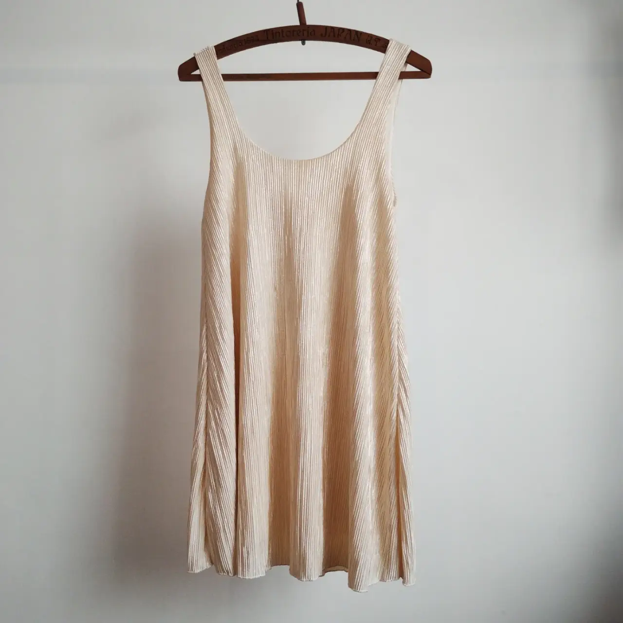 Vestido a las rodillas plisado en color crudo/dorado, ideal para un look elegante y fresco. Confeccionado en viscosa y poliéster, perfecto para diversas ocasiones. Con forro.