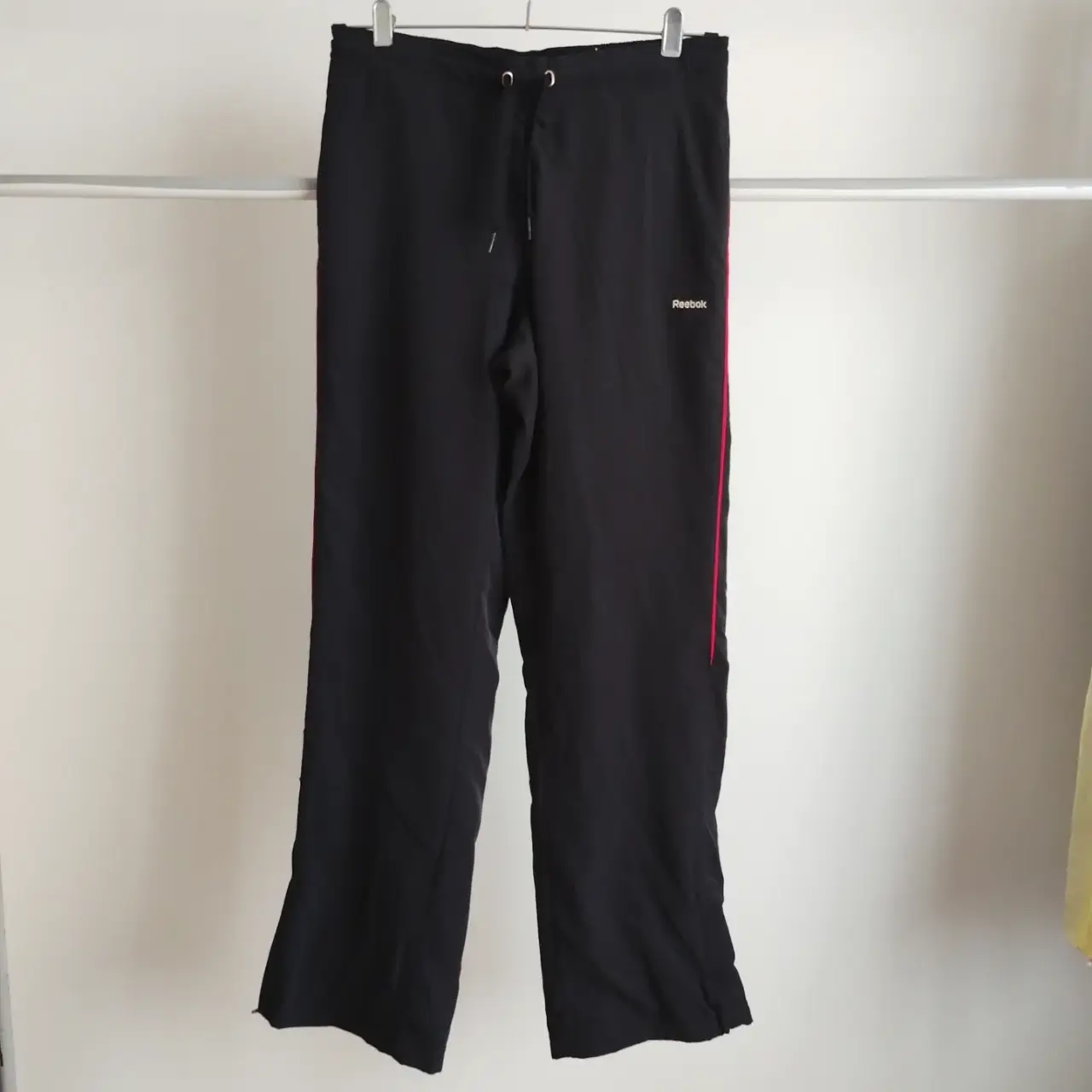 Pantalón deportivo negro Reebok, con detalles en rojo en los laterales. Talle M. Ideal para actividades físicas o uso casual. va para t.28. forro de red. cierre en botamanga