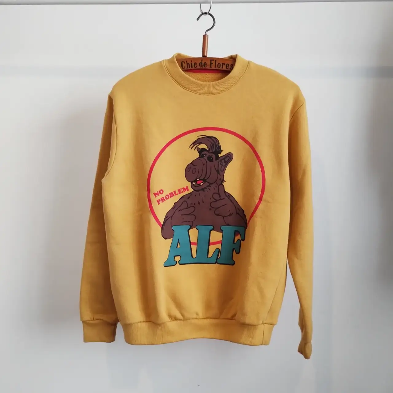 Buzo de cuello redondo amarillo con estampado de ALF. Diseño retro/vintage. Ideal para un look casual y cómodo. tiene dos manchitas. frizado y abrigado.
