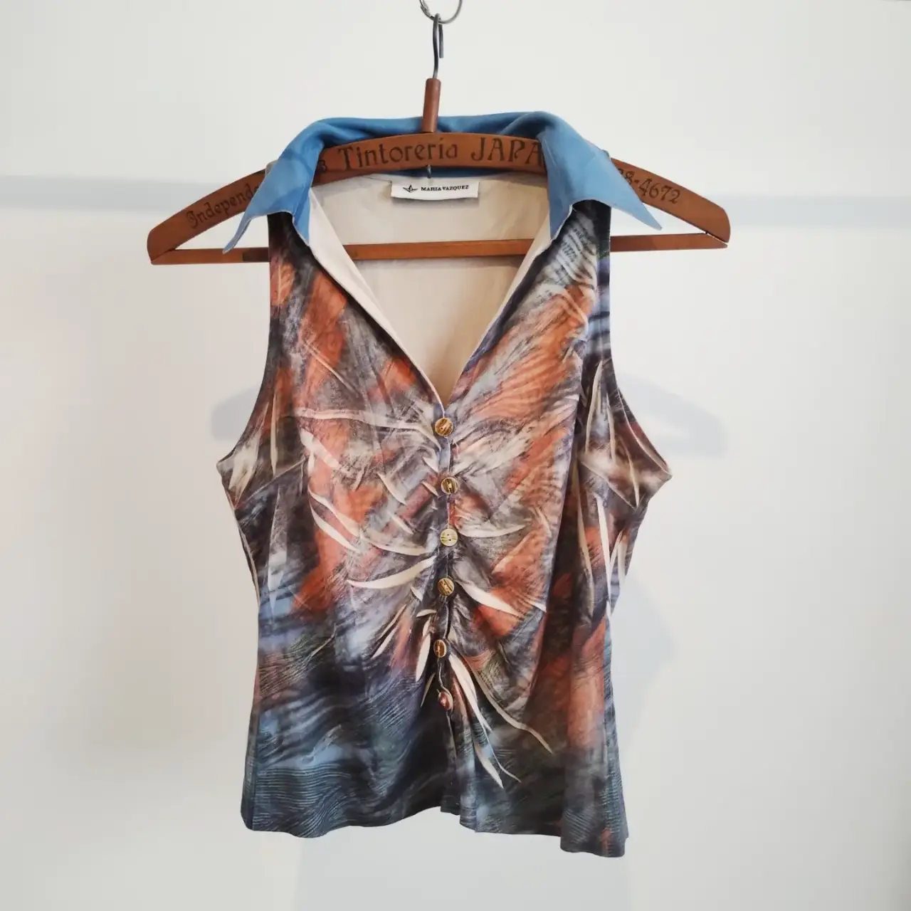 top sin mangas con estampado abstracto en tonos naranja, azul y blanco. Cuello camisero azul y botones. Espalda con detalles de pedrería turquesa. Ideal para un look vintage y sofisticado. talle único,  S/M