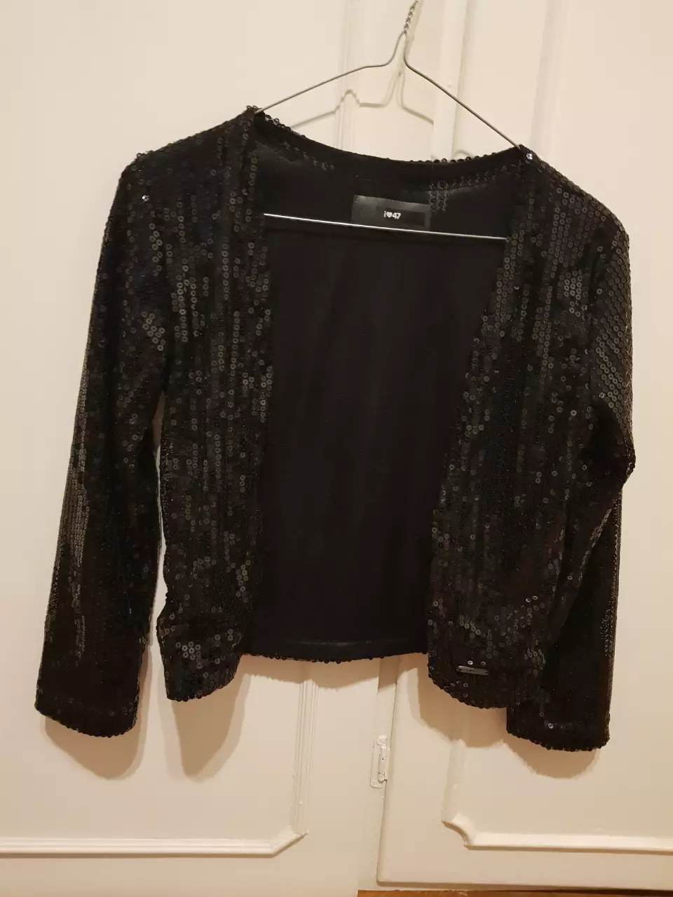 Elegante cardigan negro con lentejuelas, ideal para fiestas y eventos especiales. Un toque de brillo para destacar en cualquier ocasión.