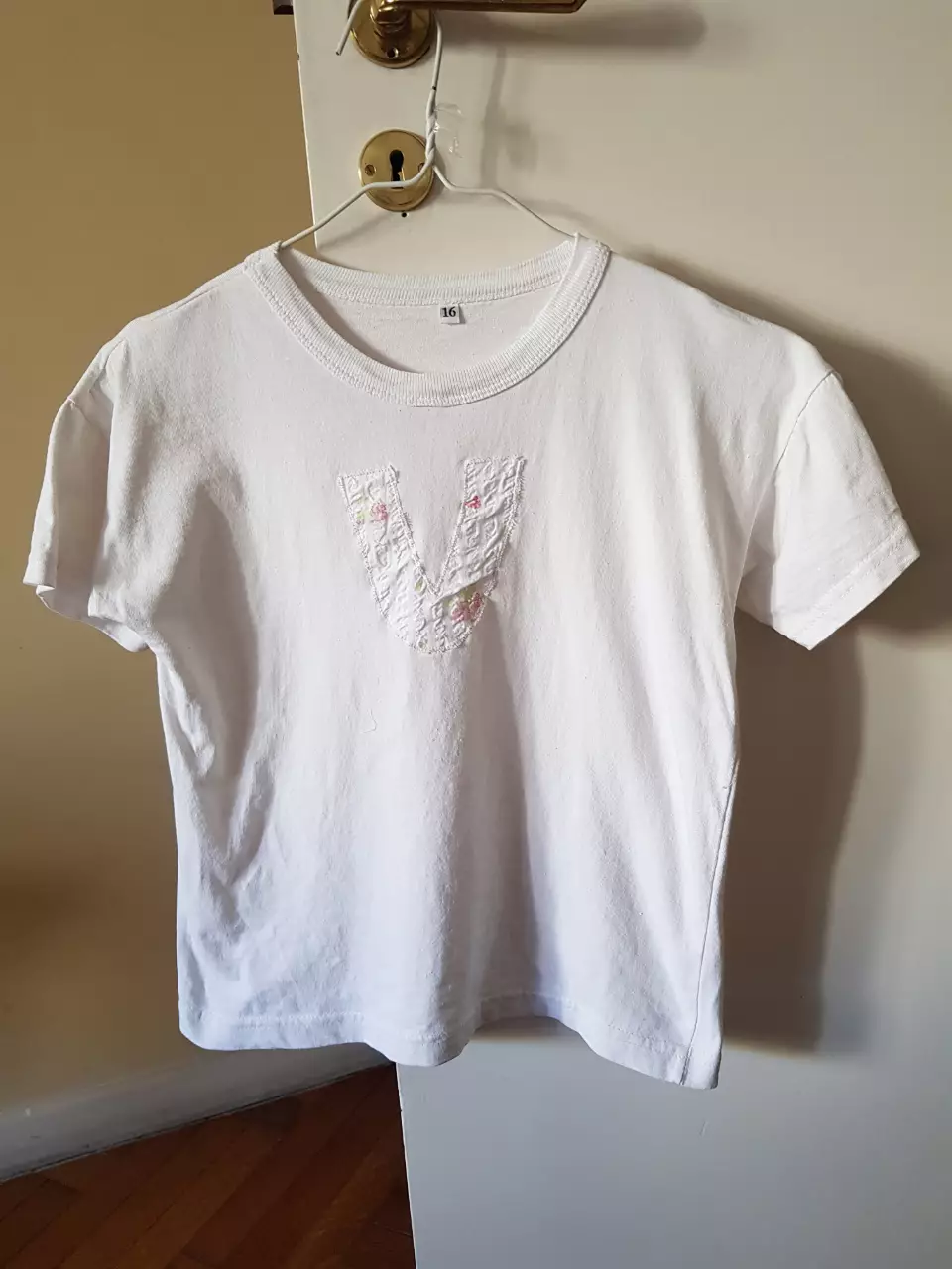 Remera blanca de algodón con detalle bordado en forma de V en el frente. Talle 14/16.