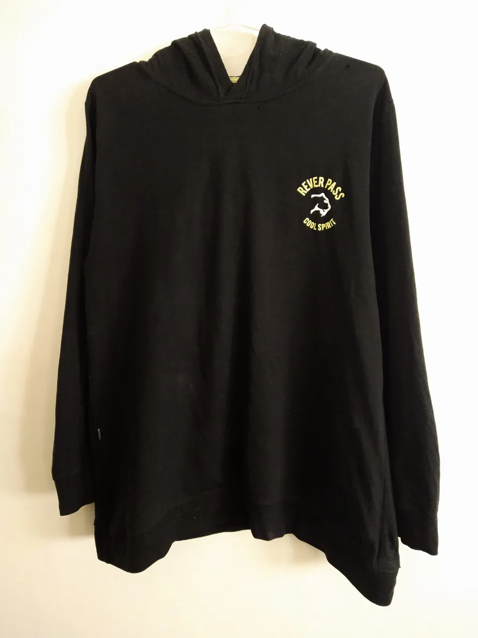 Buzo negro con capucha, manga larga y estampa "REVER PASS COOL SPIRIT" en amarillo en el frente. Ideal para un look casual y urbano. Tiene un micro agujerito cerca del cuello, lado izquierdo, se ve en foto Nro2.