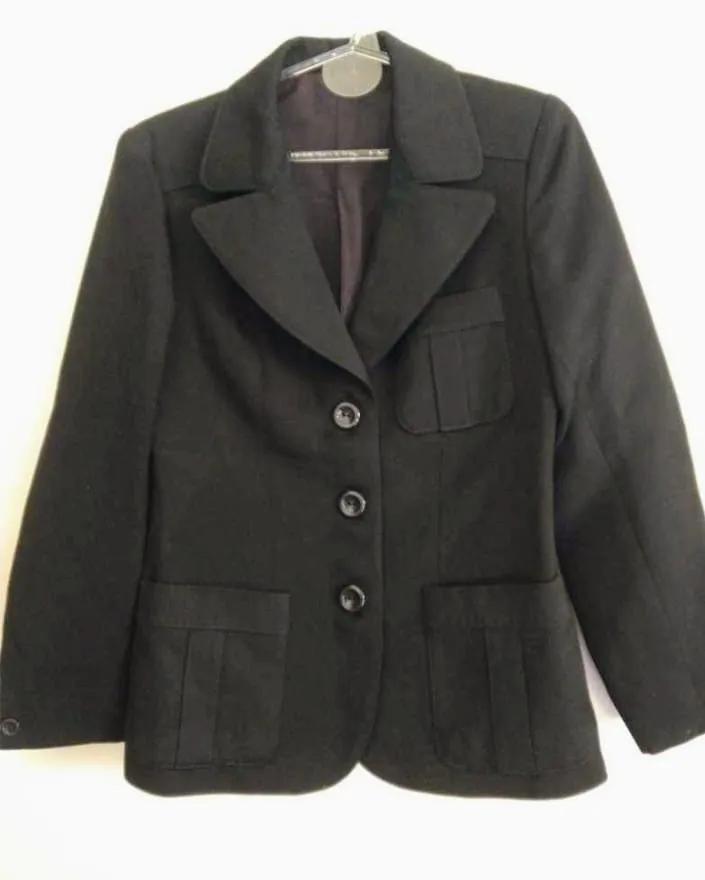 Blazer negro clásico, ideal para un look elegante y formal. Cuenta con dos bolsillos frontales con tapa y tres botones en la parte delantera. Perfecto para ocasiones de trabajo o eventos especiales.