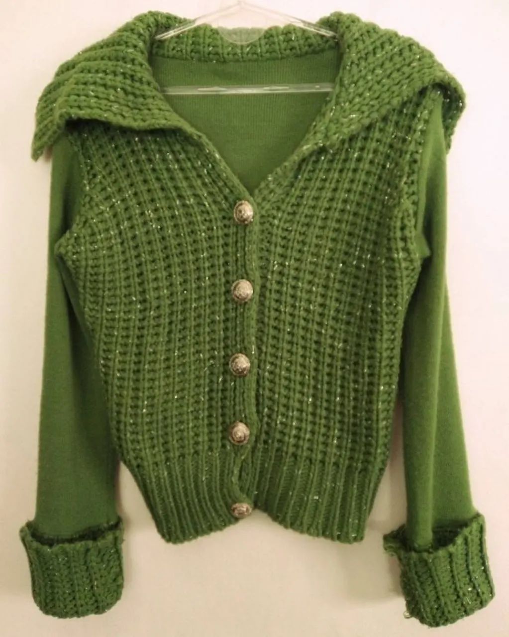 Sweater verde con botones plateados y grandes y detalles de hilos plateados brillantes (adelante y puños). Posee cuello solapa tejido y puños anchos tejidos. Le falta el 1er botón!