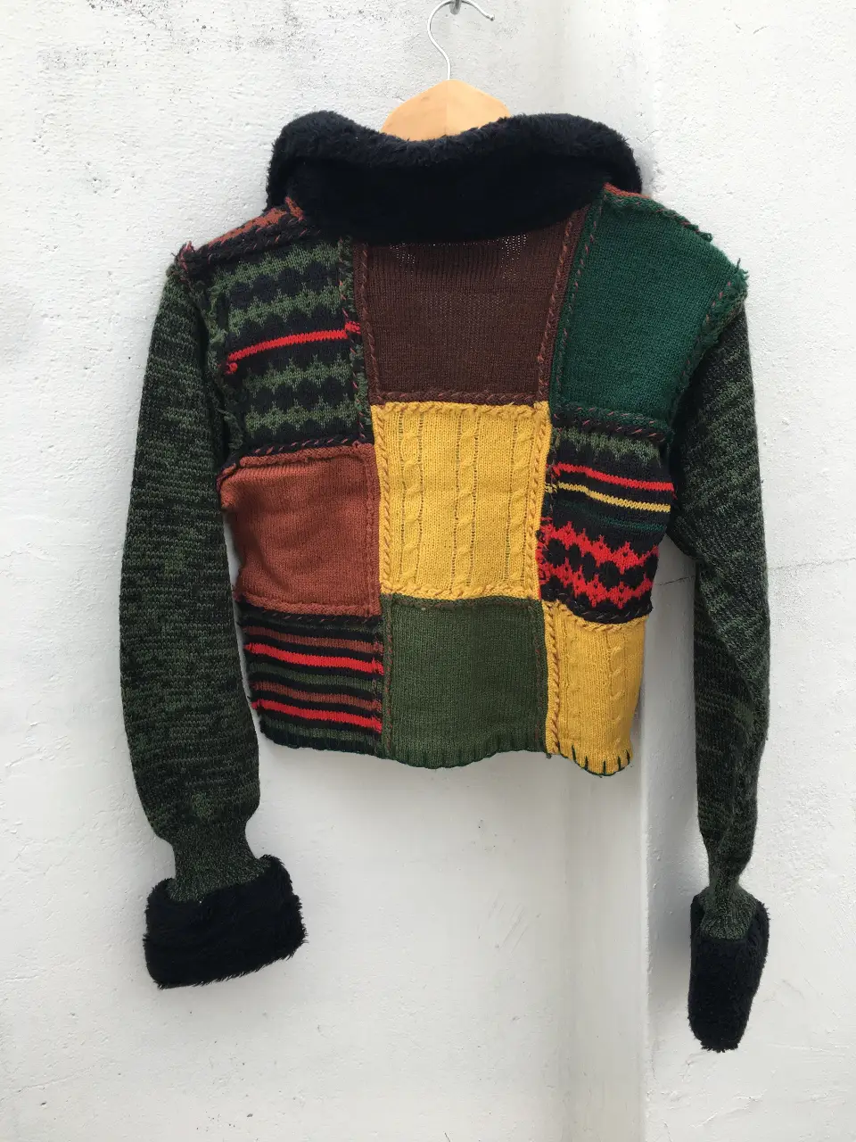 Sweater cropped patchwork con cuello alto y puños de piel sintética. Diseño único y llamativo, ideal para un look vintage y original.