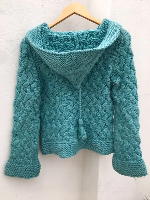 Precioso cardigan tejido a mano en color celeste, con capucha y detalles trenzados. Ideal para un look abrigado y con estilo en invierno. Perfecto para combinar con diferentes outfits.
