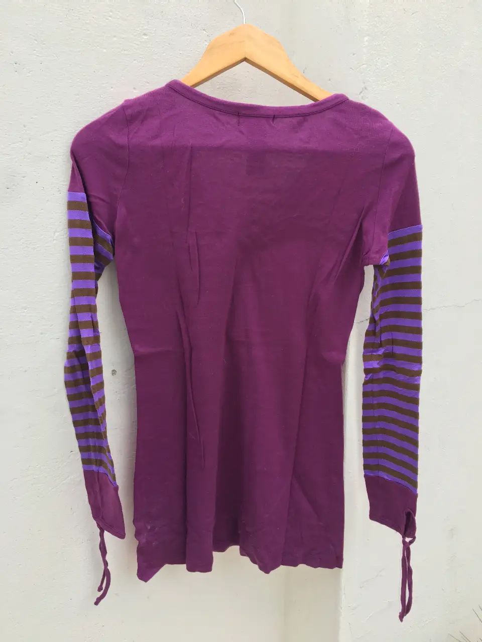 Remera manga larga de mujer, color violeta con mangas a rayas marrones y violetas. Diseño con estampado en el frente.