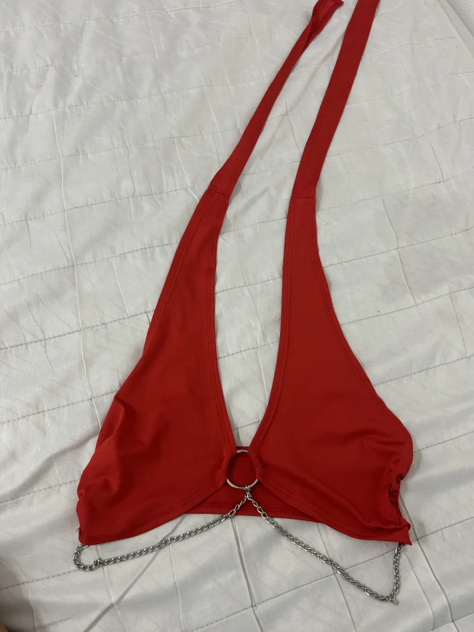 Top rojo con detalles de cadenas y argollas metálicas. Diseño audaz y moderno, ideal para destacar en cualquier salida.